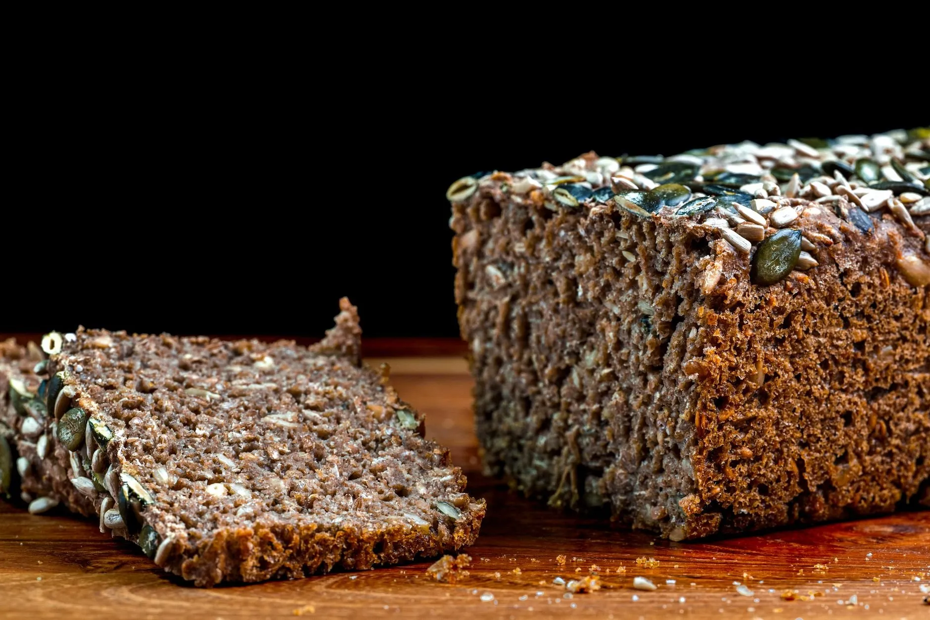 A seeded rye tin loaf with pumpkin and sunflower seeds, one thick slice cut
