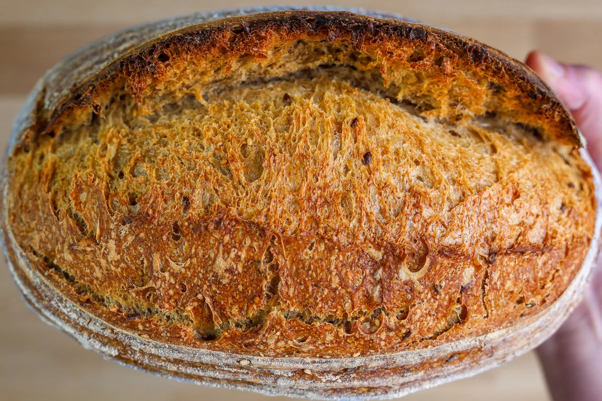 Close-up of a scored artisan sourdough loaf with a deep golden crust.